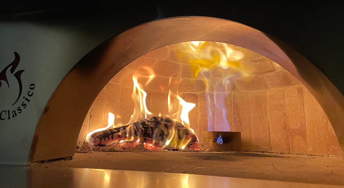 Wood burning along with the gas burner inside a Forno Classico Brick Pizza Oven