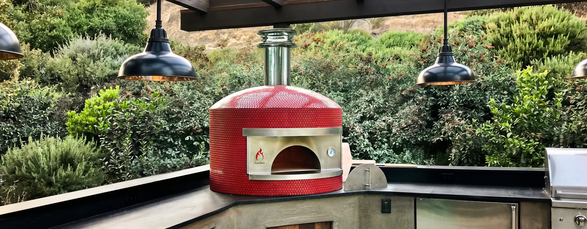 Forno Classico Napoli pizza oven on a patio with greenery in the background
