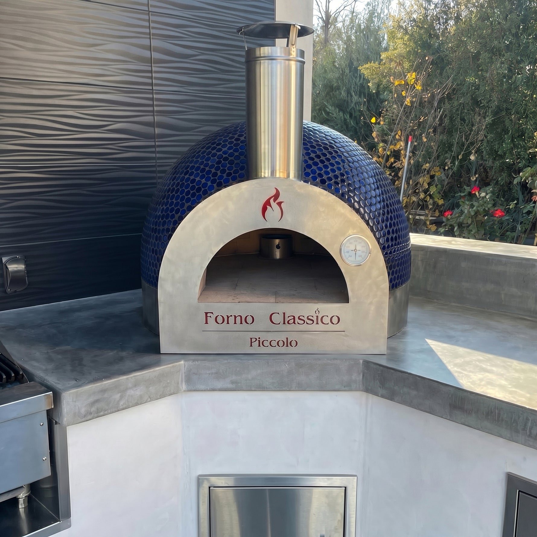 Forno Classico Piccolo 65 pizza oven with blue mosaic design on a concrete surface