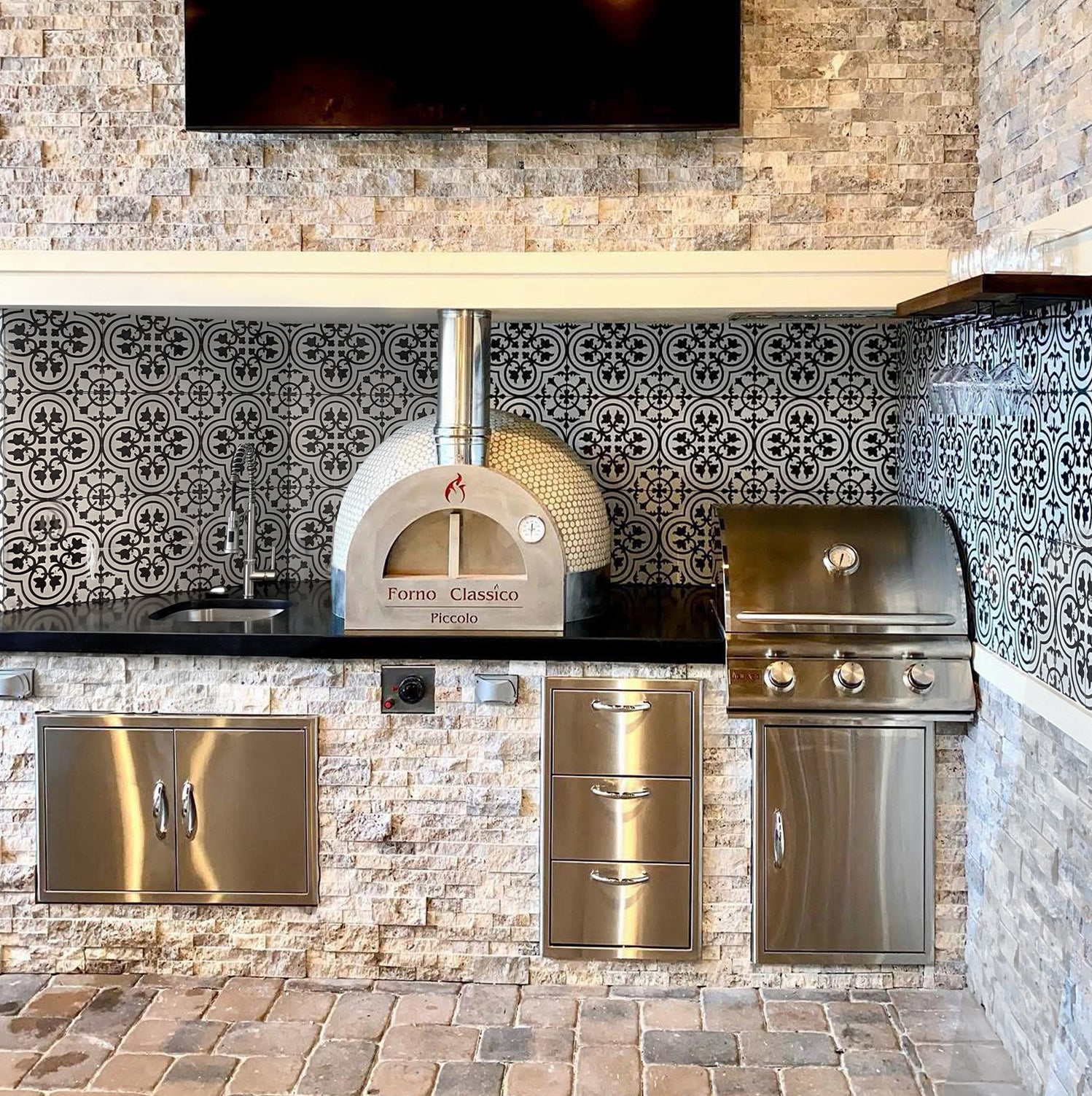 Forno Classico Piccolo 65 kitchen with pizza oven, grill, and decorative tile backsplash.