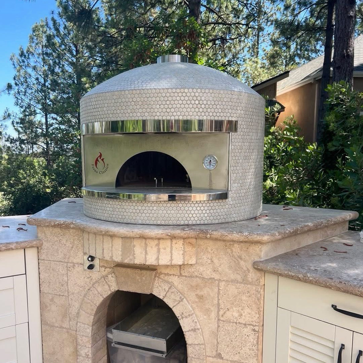 Forno Classico pizza oven with stone base in a garden setting