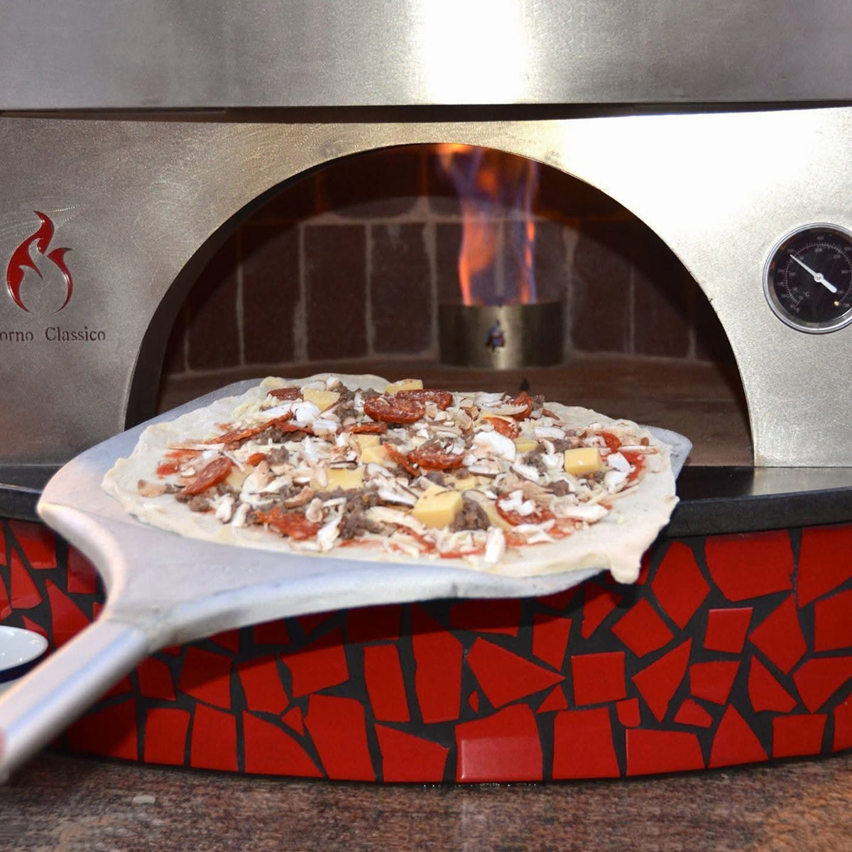 Forno Classico wood-fired oven with a pizza being taken out using a peel.