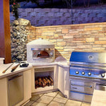 Outdoor kitchen with stone wall, Forno Classico pizza oven, and grill.