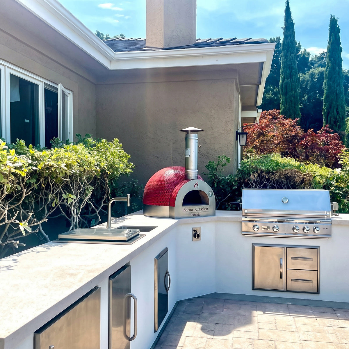 Outdoor kitchen with a Forno Classico Piccolo 65 pizza oven and stainless steel grill.